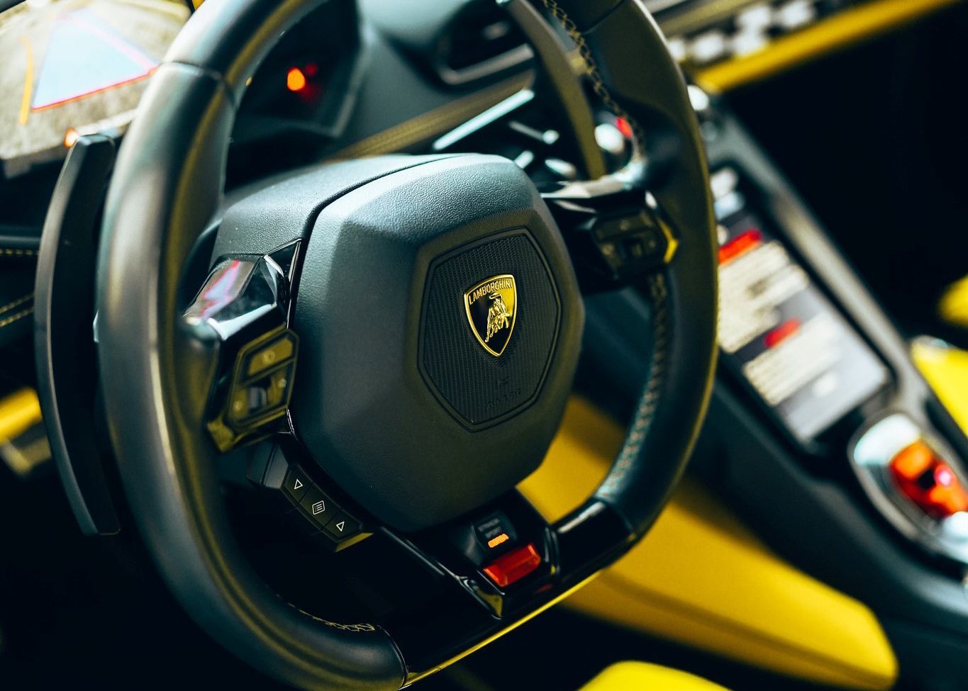 A close up of a Lamborghini steering wheel in a car.