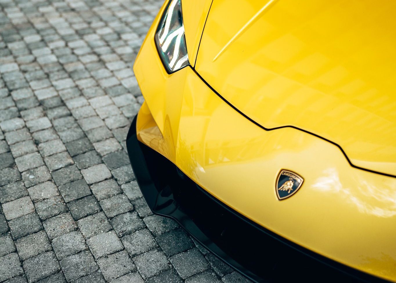 A yellow Lamborghini Huracan is parked on a cobblestone driveway.