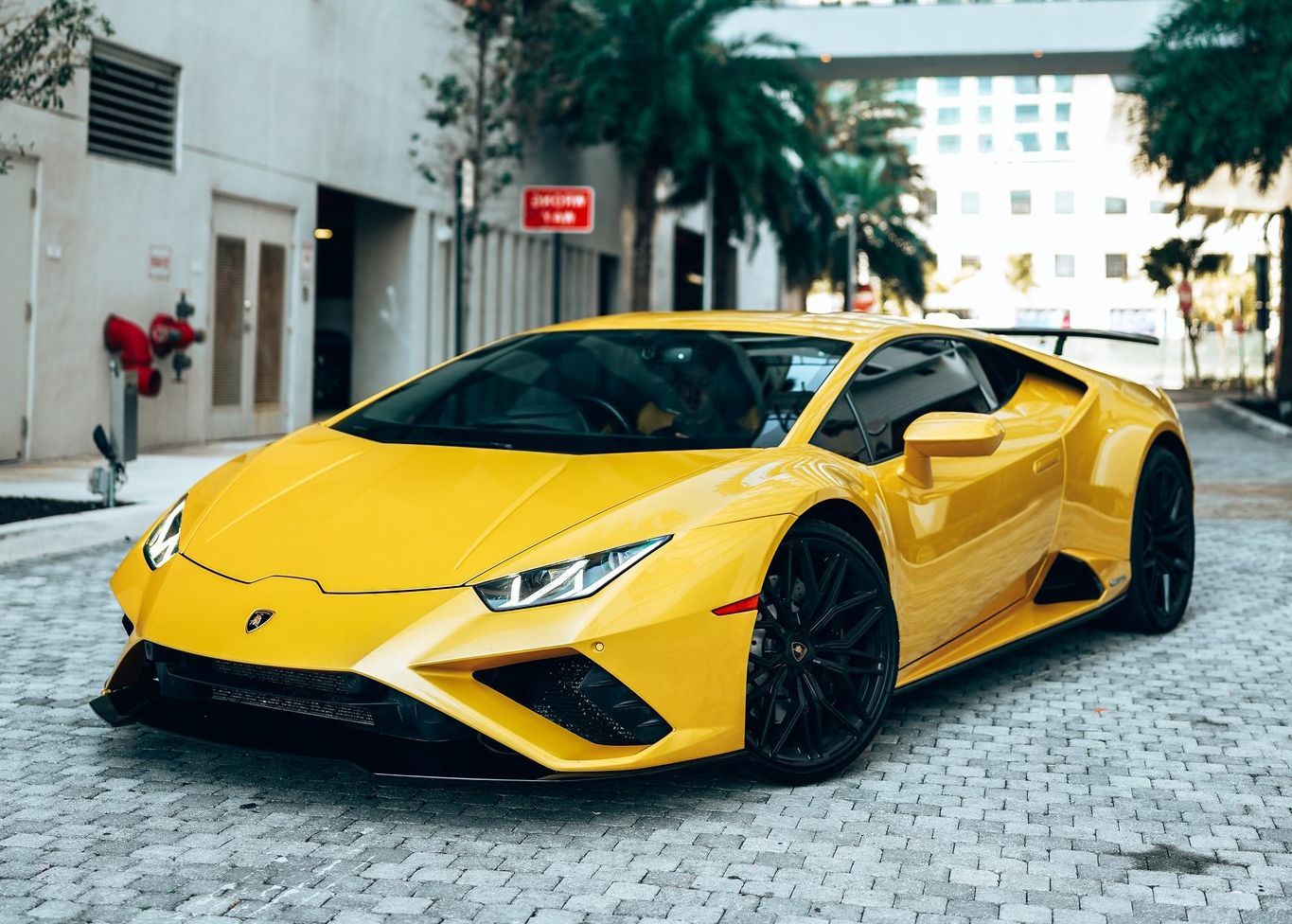 A yellow Lamborghini Huracan is parked on a cobblestone street.