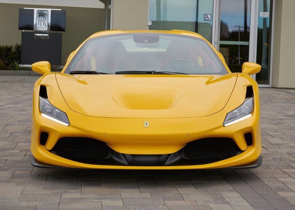 A yellow sports car is parked in front of a building.