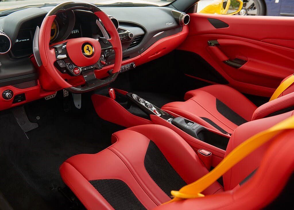The interior of a Ferrari sports car with red seats.