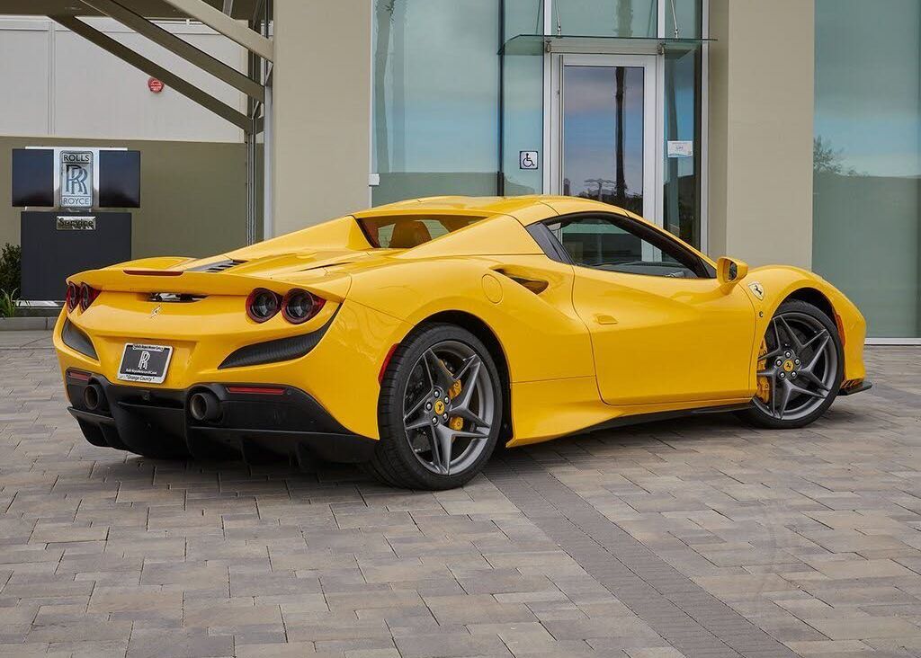 A yellow sports car is parked in front of a building.
