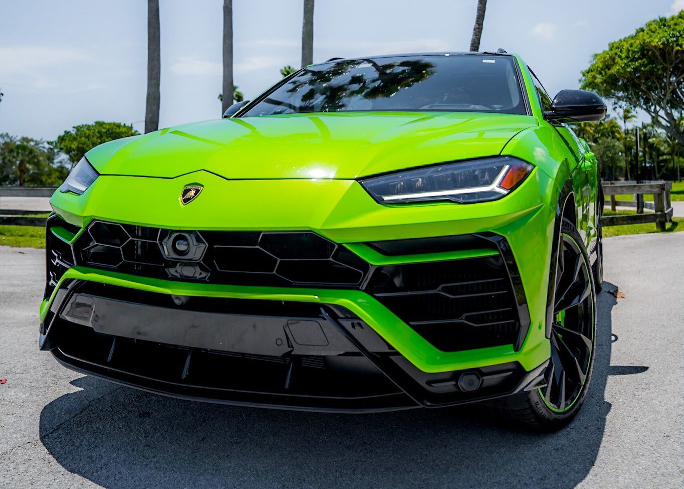 A green Lamborghini Urus is parked on the side of the road.
