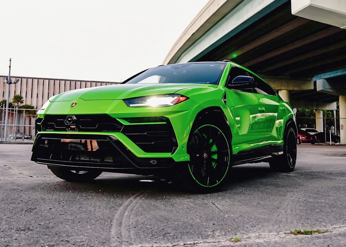 A green Lamborghini Urus is parked under a bridge.