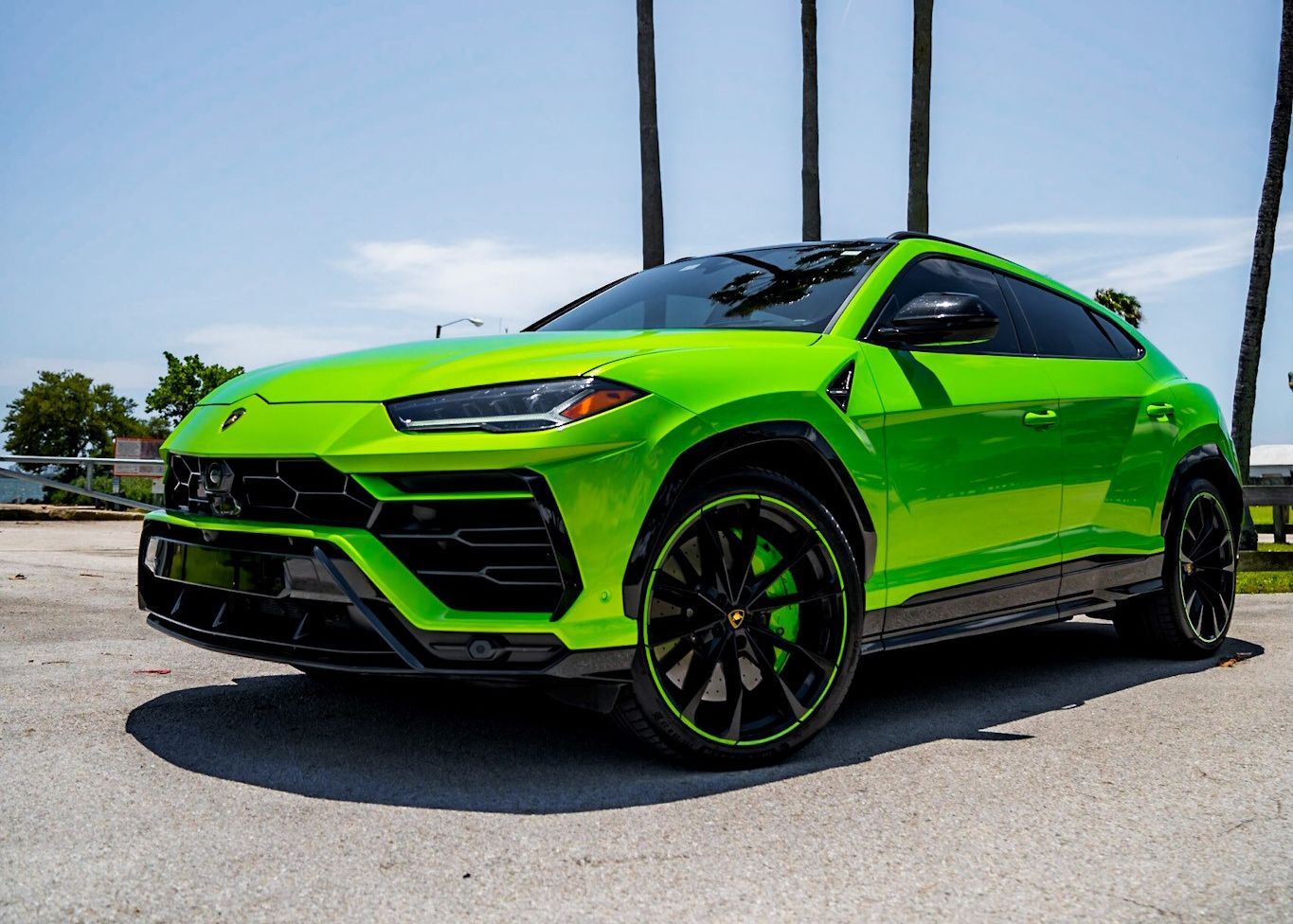 A green Lamborghini Urus is parked on the side of the road.