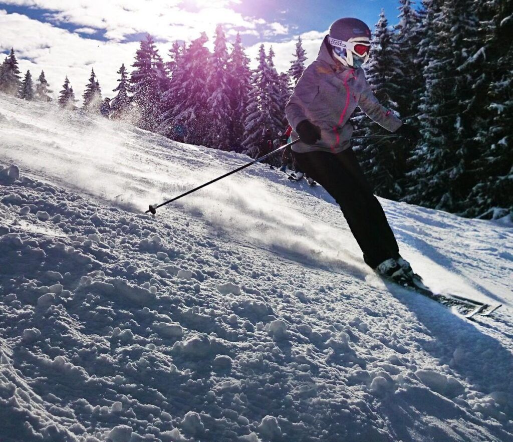 A person skiing down a snow covered slope with trees in the background