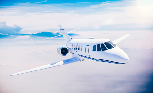 A private jet is flying through the clouds in the sky.