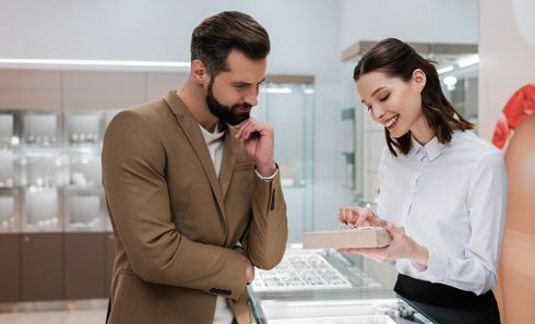 A man and a woman are looking at jewelry in a jewelry store.