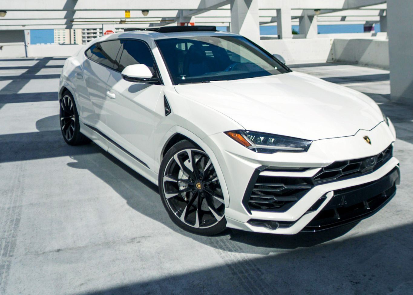 A white Lamborghini Urus is parked in a parking garage.