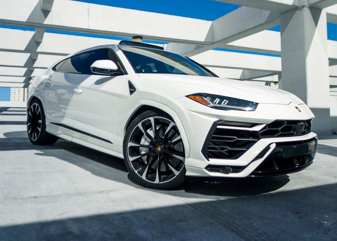 A white Lamborghini Urus is parked in a parking garage.
