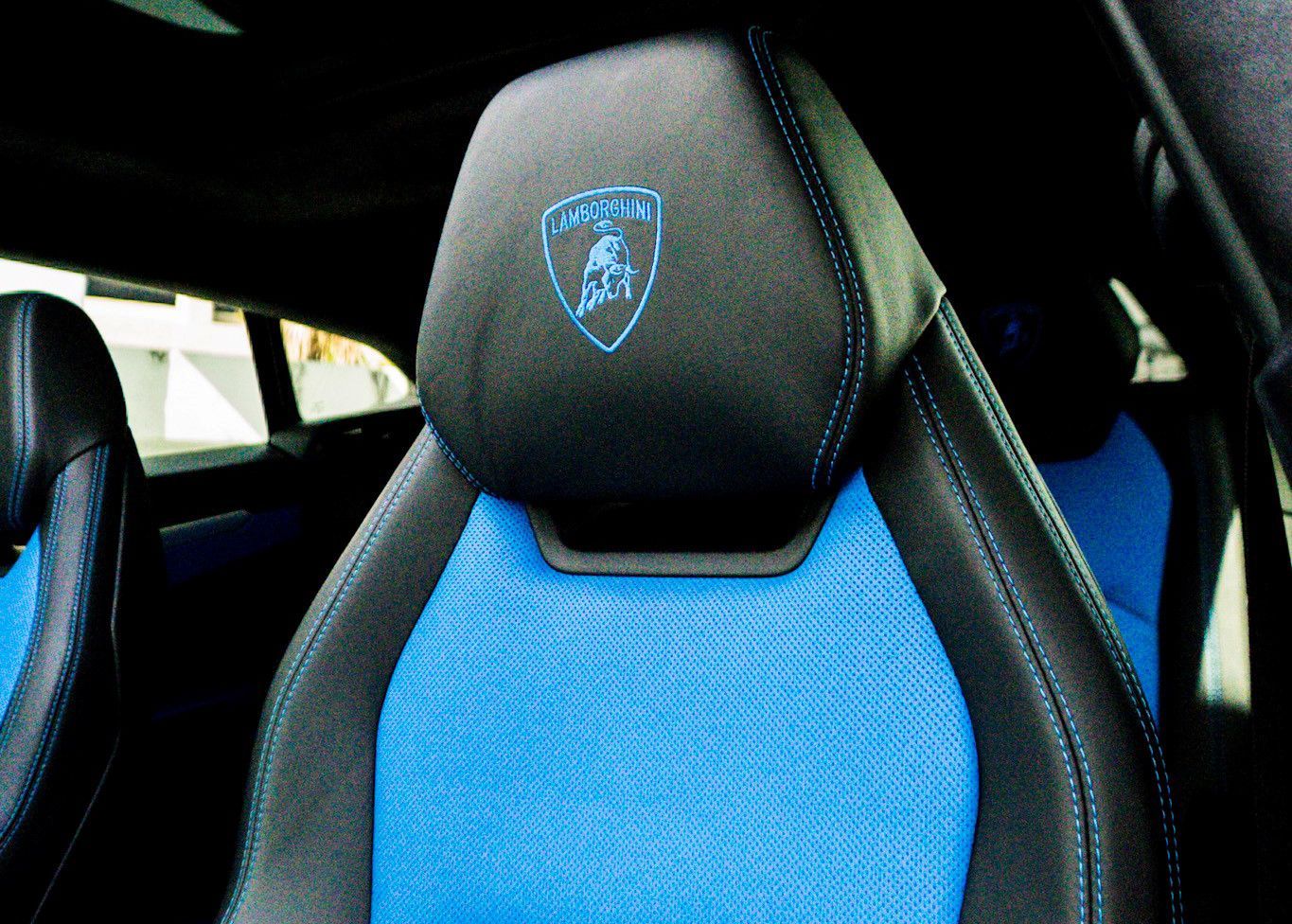 A black and blue car seat with a Lamborghini logo on it.