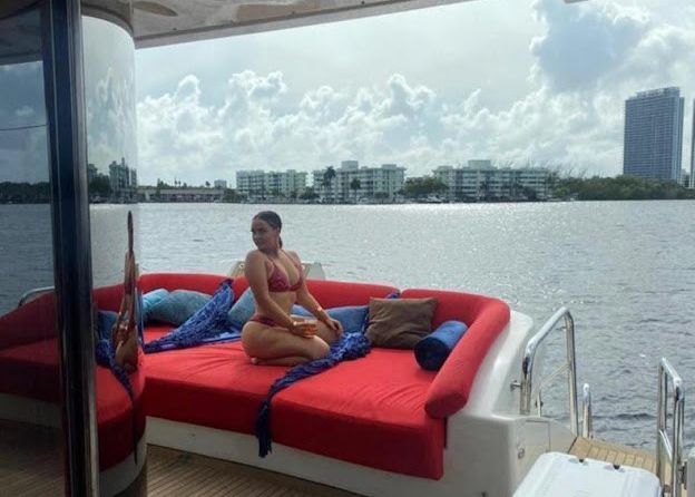 A woman in a bikini is sitting on a boat in the water.