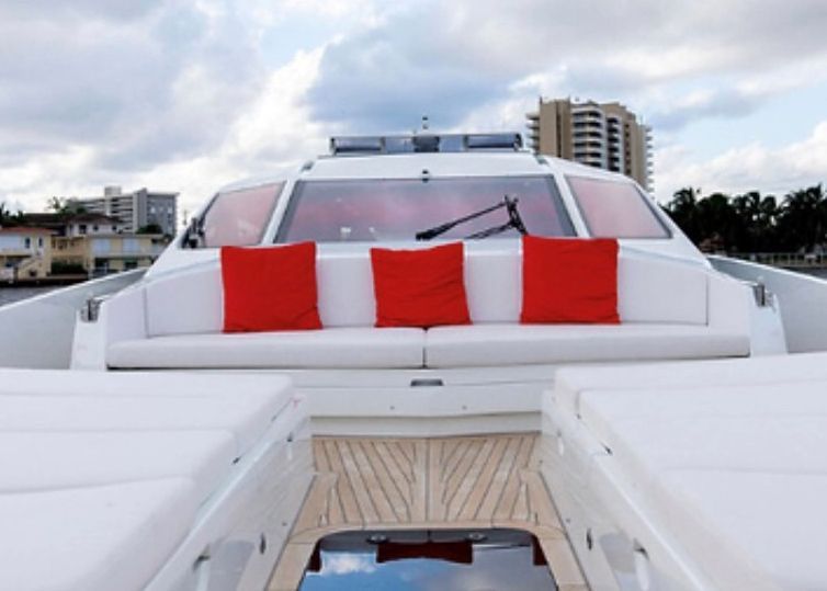 The front of a white boat with red pillows on it.