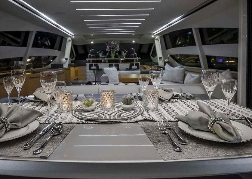 A dining table with plates, silverware, candles and wine glasses on a boat.