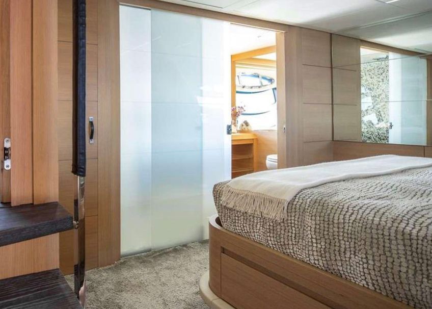 A bedroom with a bed and a sliding glass door leading to a bathroom.