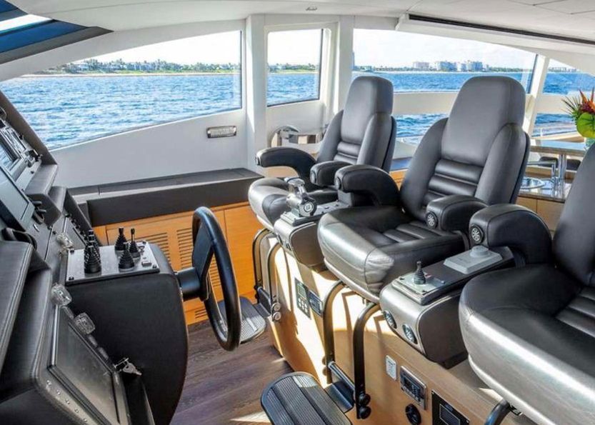 The inside of a boat with a steering wheel and seats.