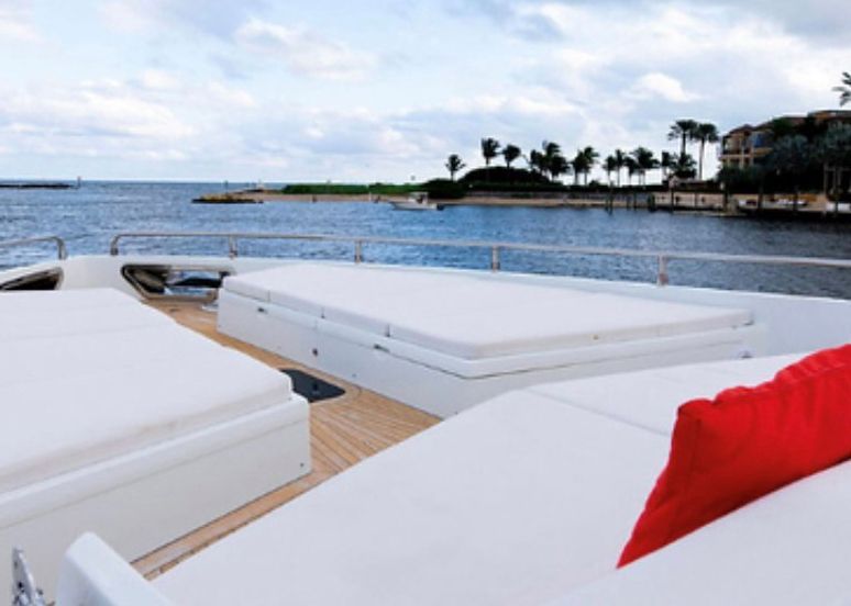 A boat with white cushions and a red pillow on the deck.