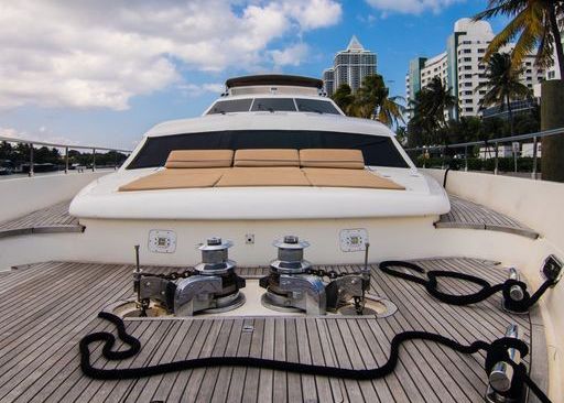 The back of a white yacht with a wooden deck.