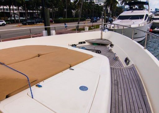 A white boat with a wooden deck is docked in the water.