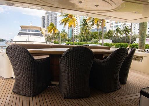 There is a table and chairs on the deck of a boat.