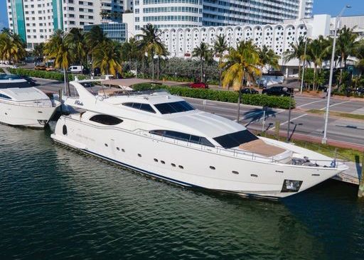 A large white yacht is docked in a harbor.