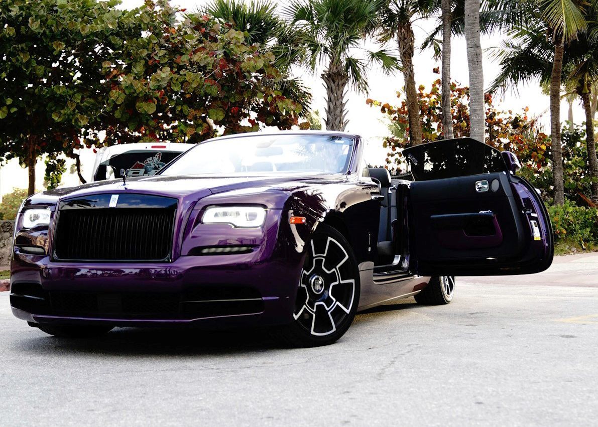 A purple car is parked in a parking lot with its doors open.