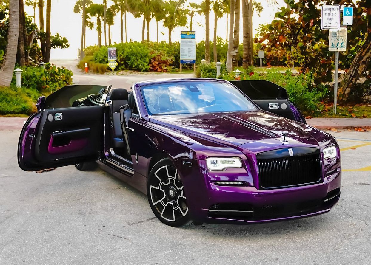 A purple car is parked in a parking lot with its doors open.