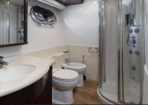 A bathroom with a toilet, bidet, sink and shower.