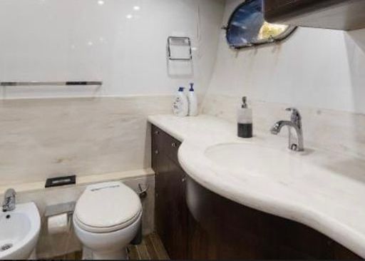 A bathroom on a boat with a toilet, sink and bidet.