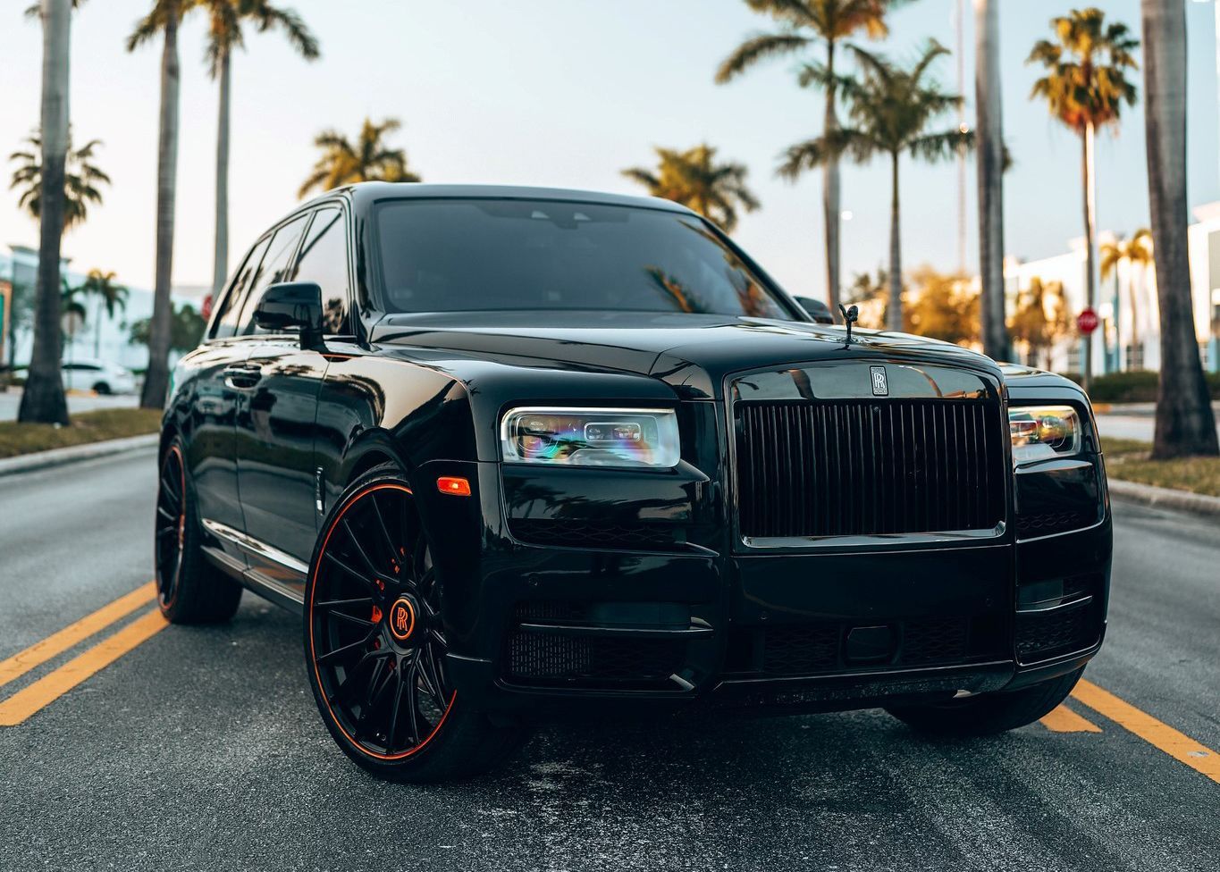 A black Rolls Royce Cullinan is parked on the side of the road.