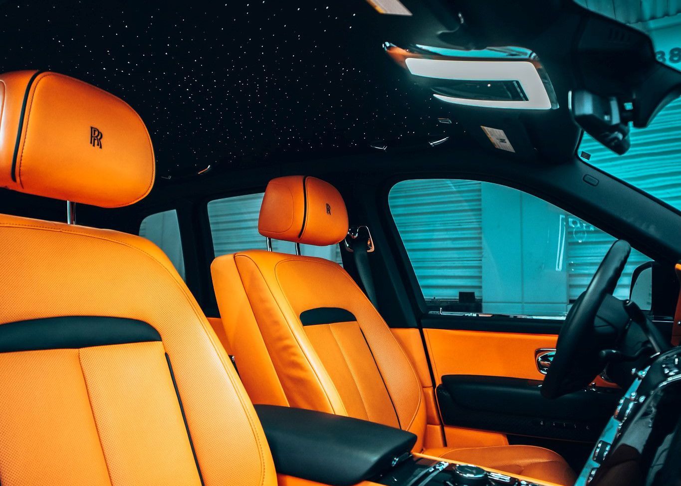 The interior of a Rolls Royce car with orange seats.