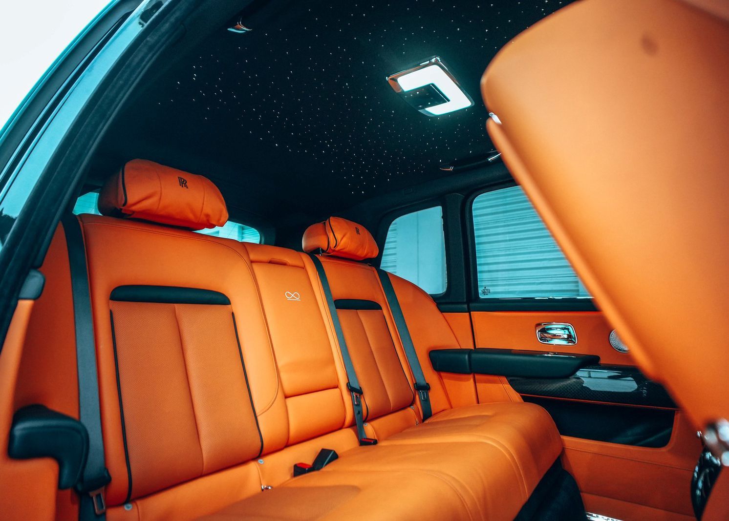 The back seat of a car with orange seats and a black ceiling.