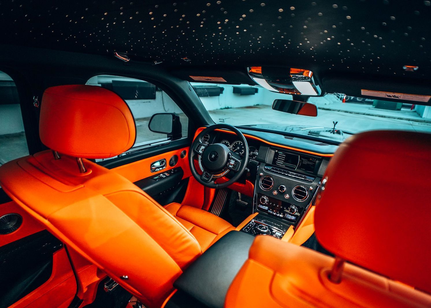The interior of a car with orange seats and a steering wheel.