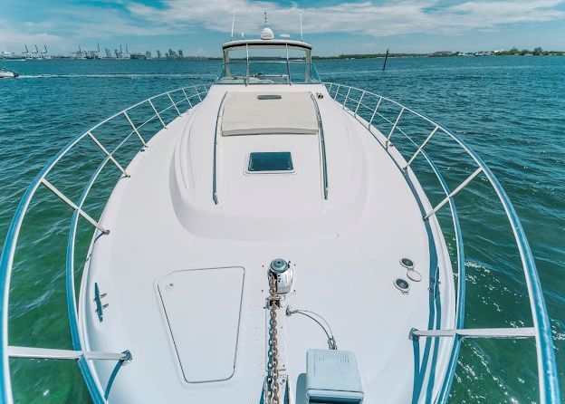 The front of a white boat is floating on top of a body of water.