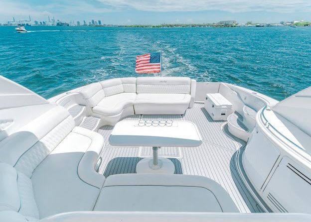 The front of a white yacht with a table and chairs in the water.