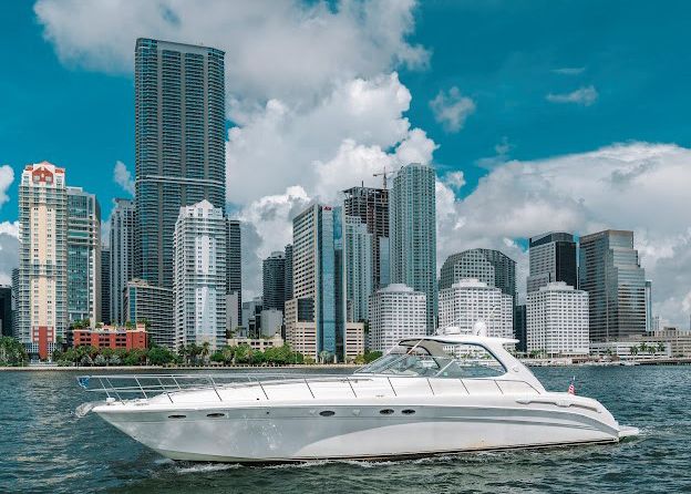 A white yacht is floating on top of a body of water in front of a city skyline.