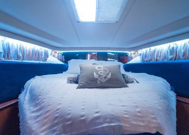 A bed on a boat with a pillow with an anchor on it.