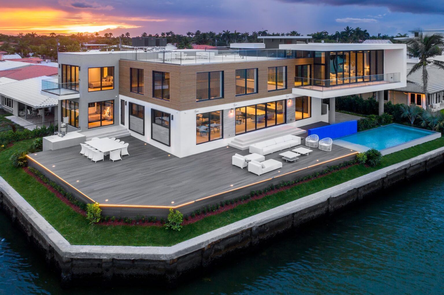 An aerial view of a large house on a small island in the middle of a body of water.