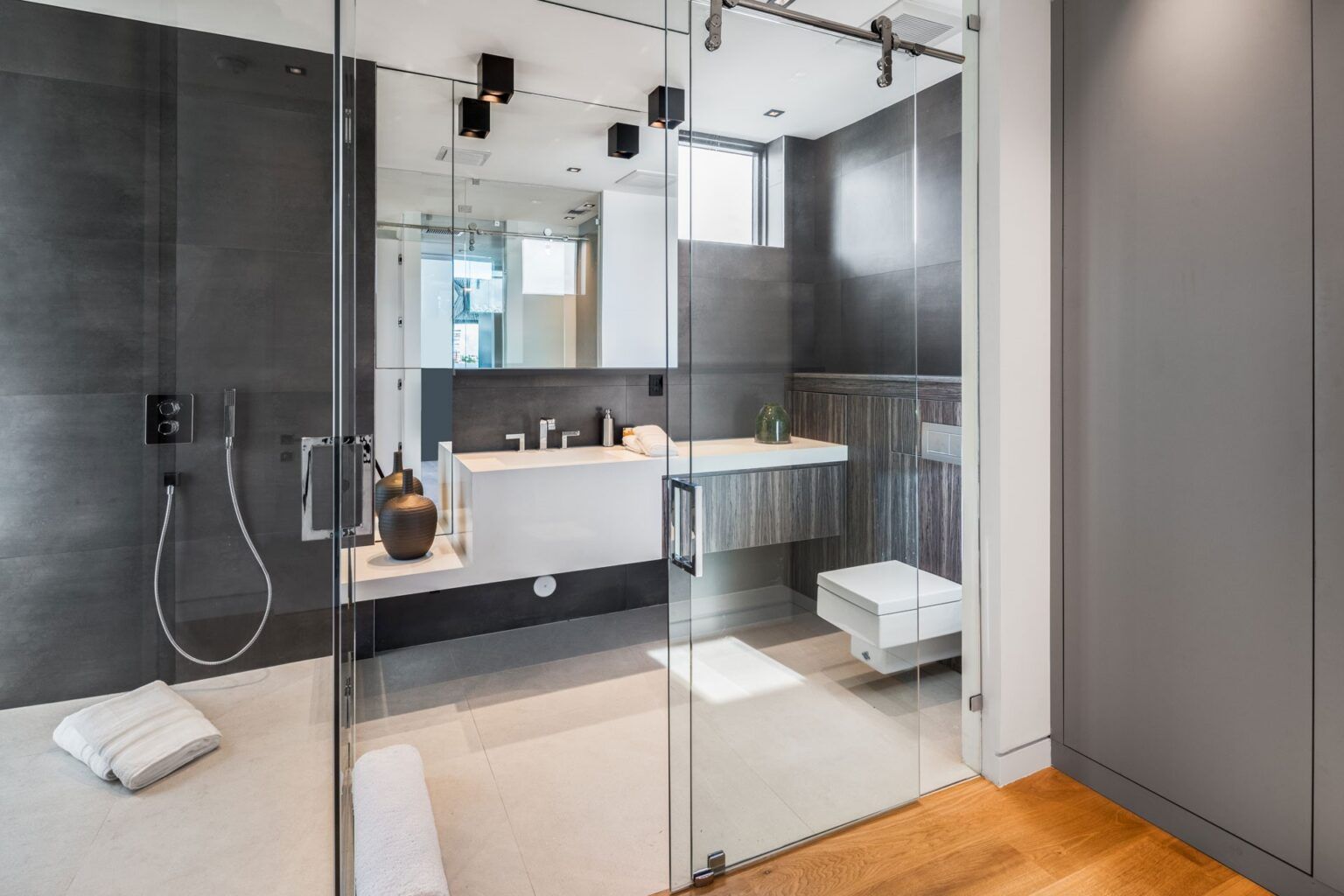 A bathroom with a walk in shower, sink, toilet and mirror.