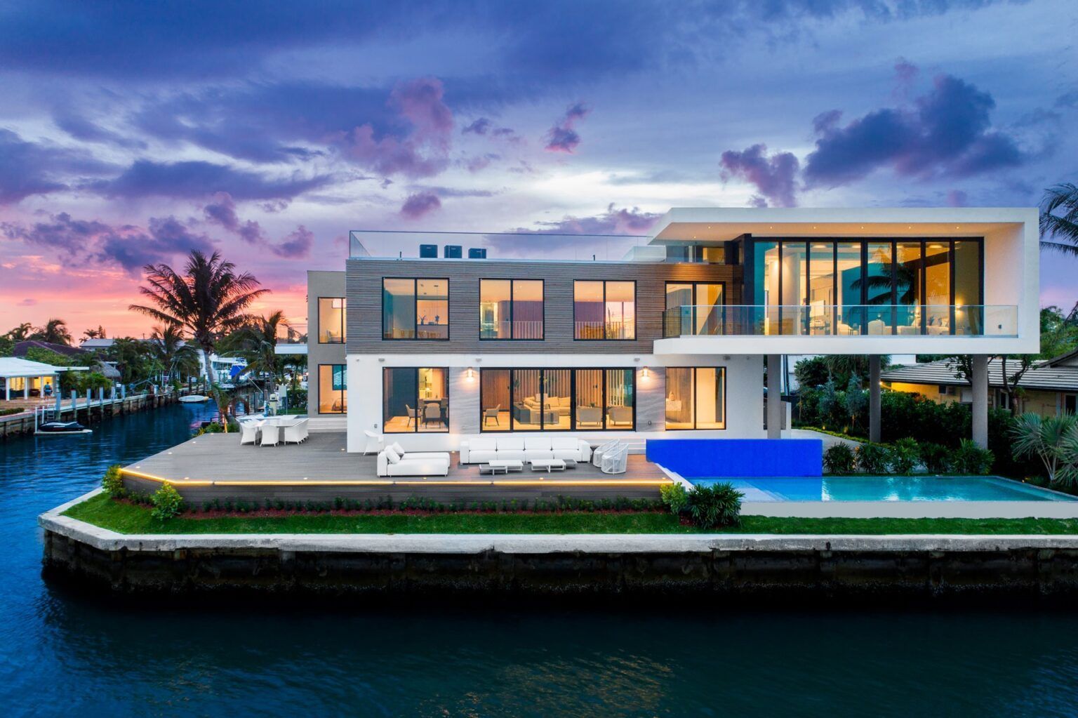 A large modern house with a swimming pool is sitting on top of a body of water.