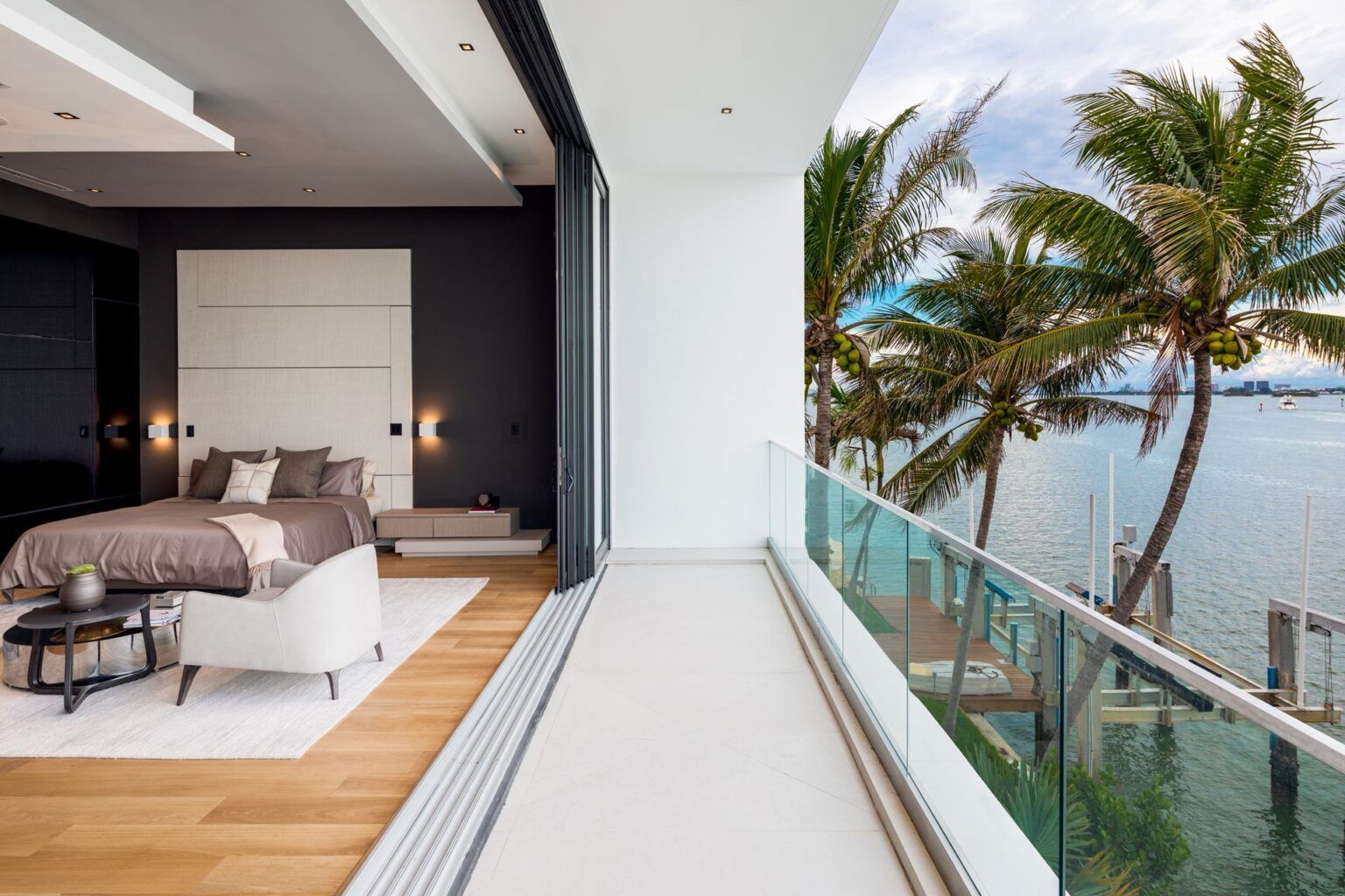 A bedroom with a large bed and a balcony overlooking the ocean.