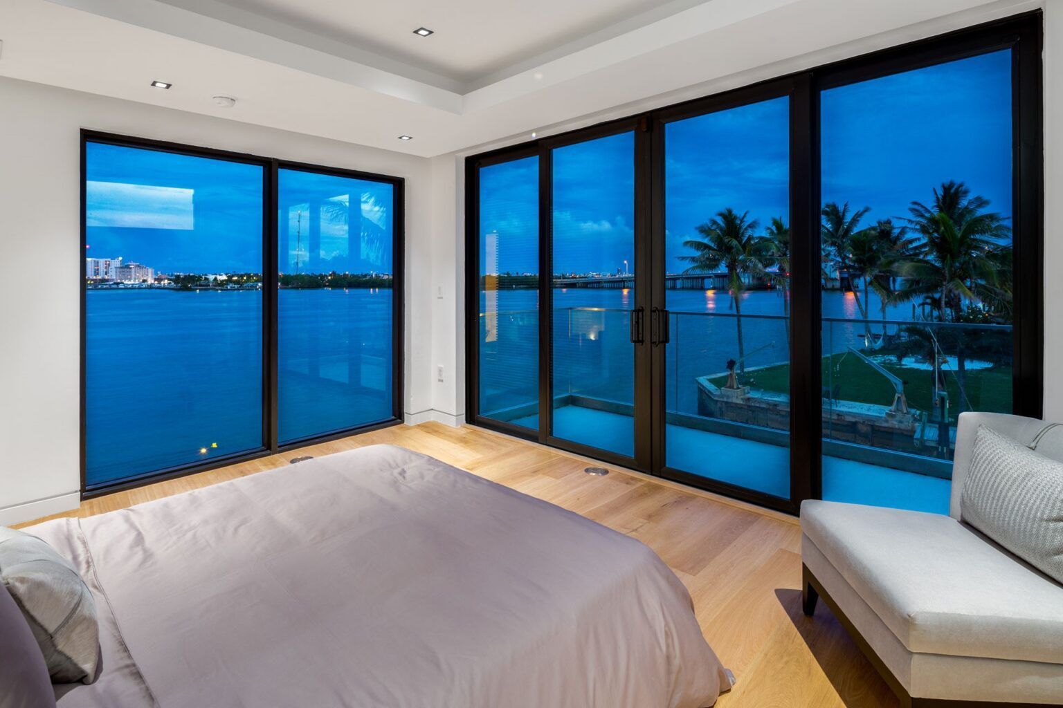 A bedroom with a large bed and lots of windows overlooking the ocean.