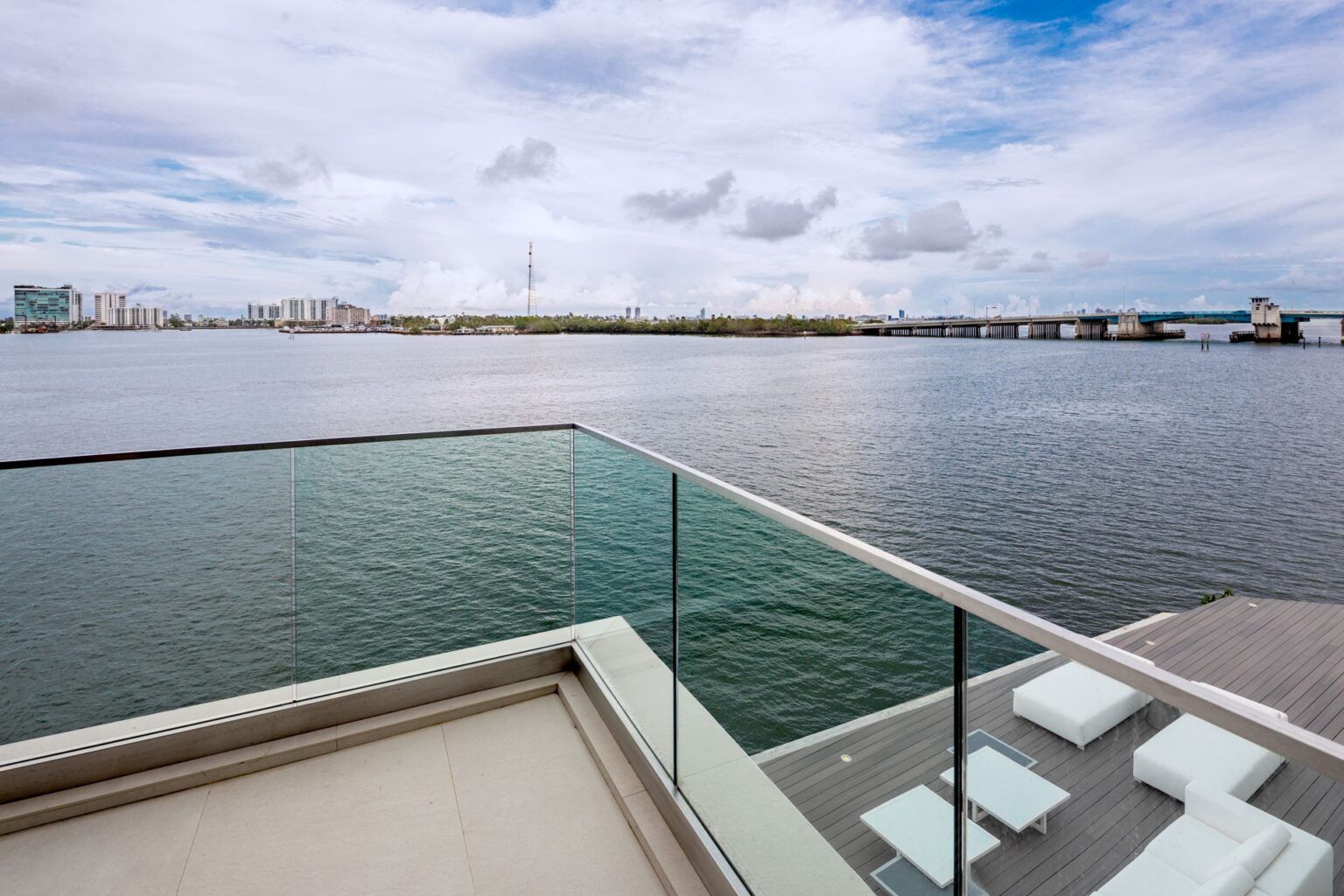 A balcony with a glass railing overlooking a body of water.