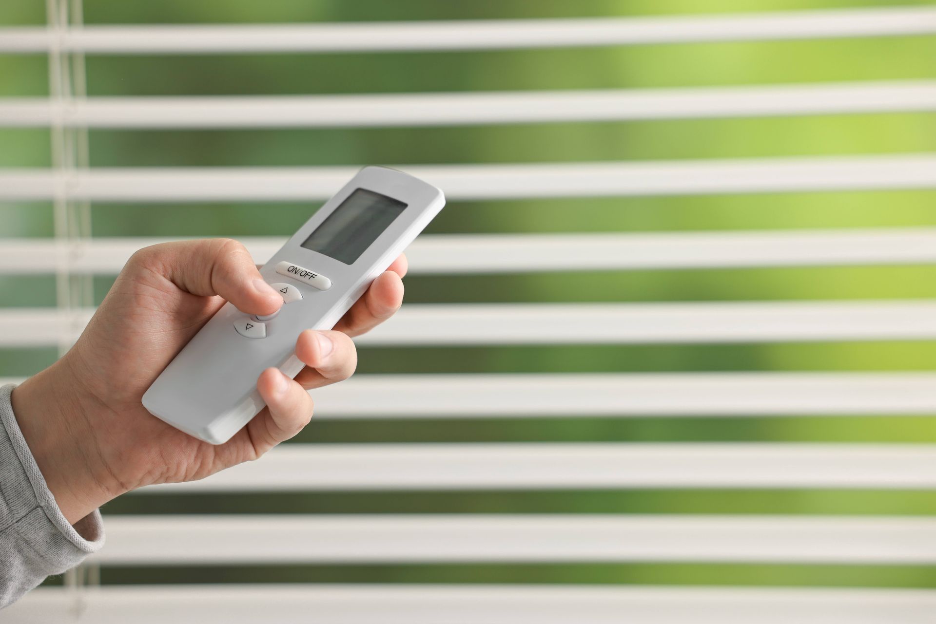 A person holding a remote control for their automatic blinds near Toledo, OH