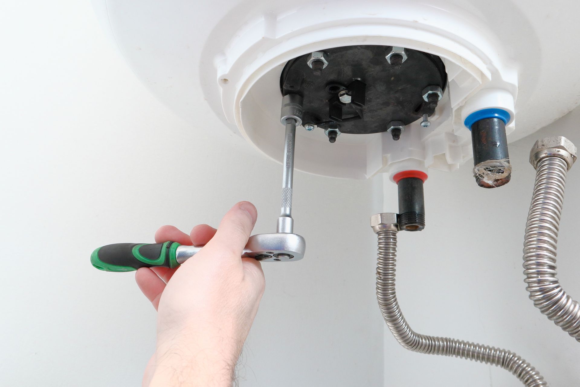 A person is fixing a water heater with a wrench.