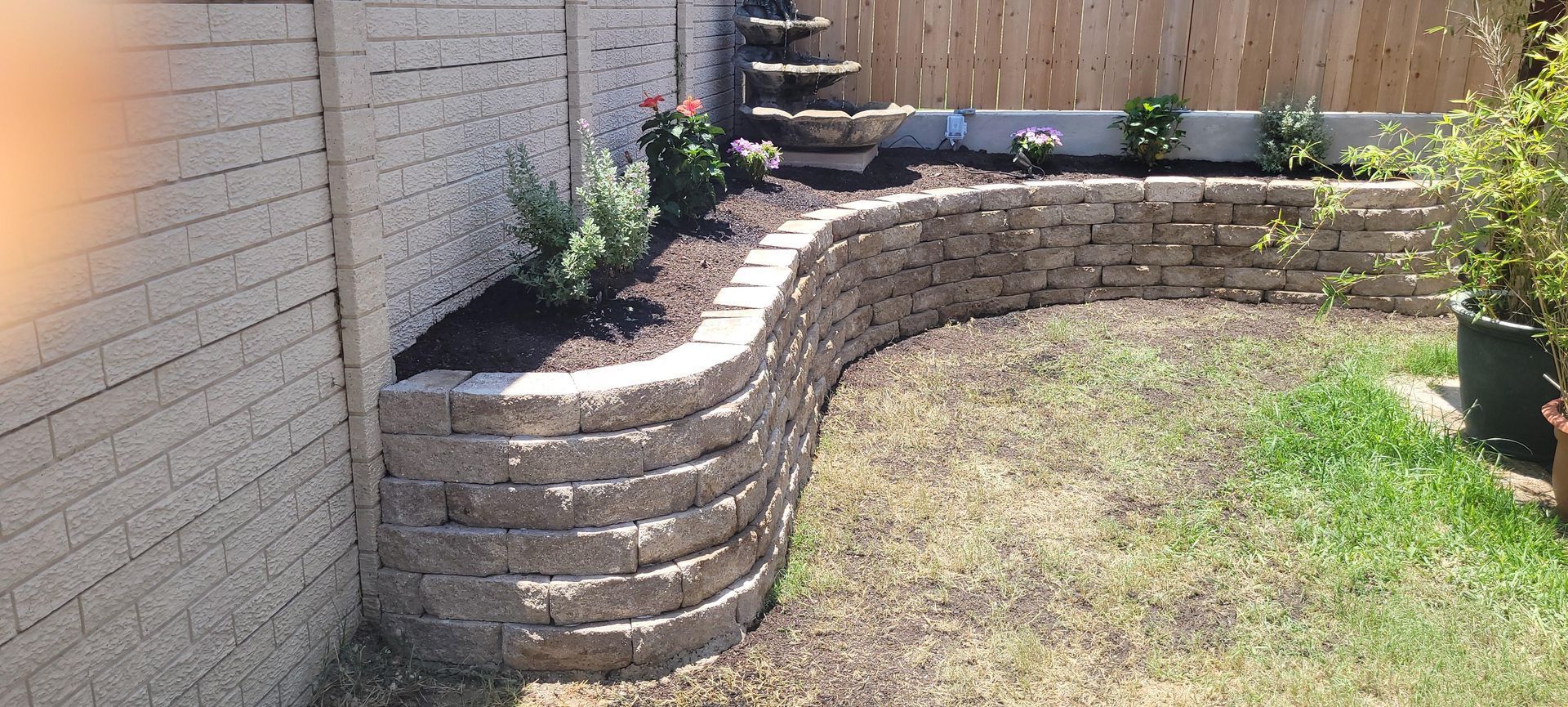 A backyard with a brick wall and a fence