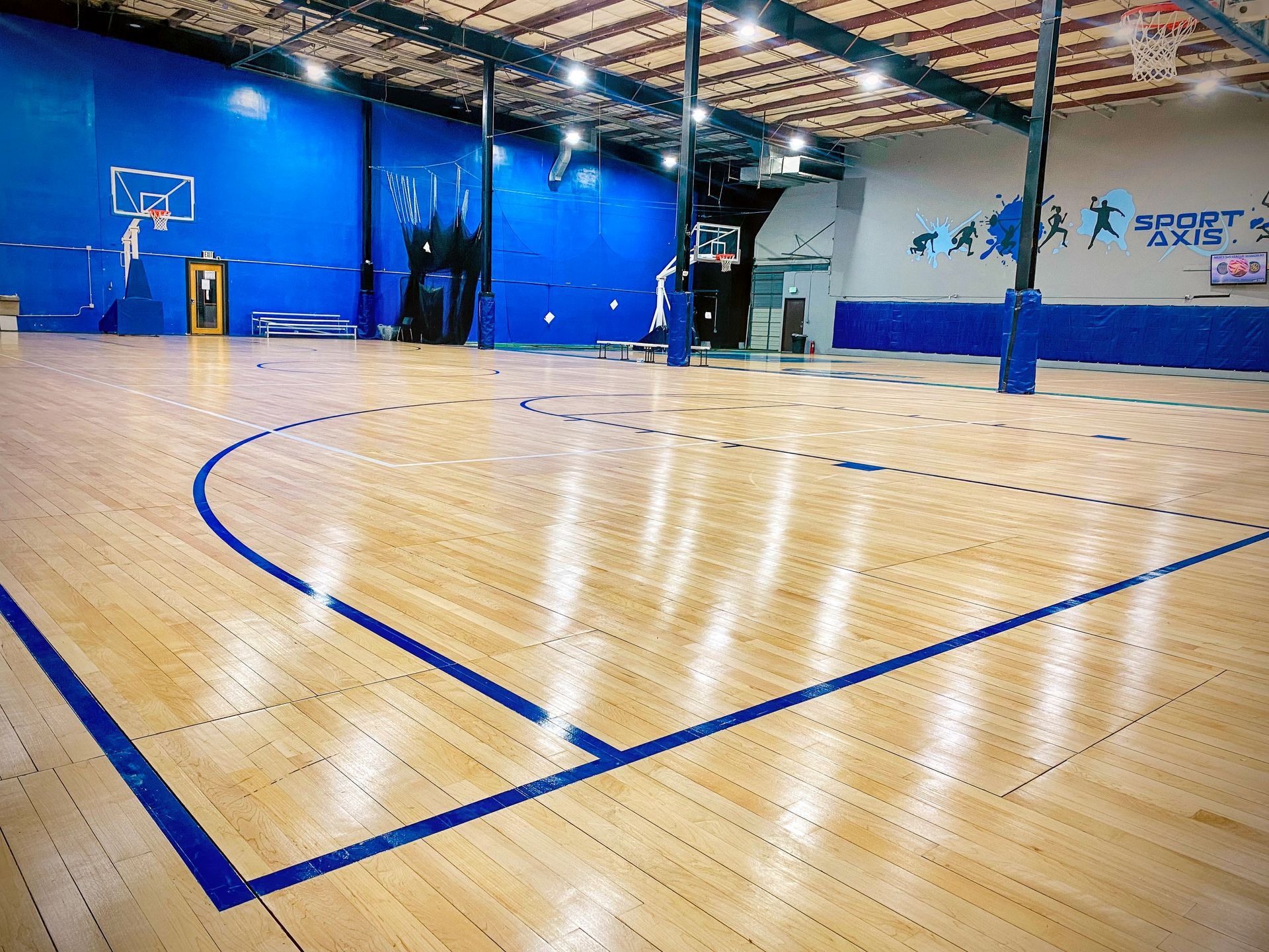 Indoor basketball court with blue accents and wooden floor.