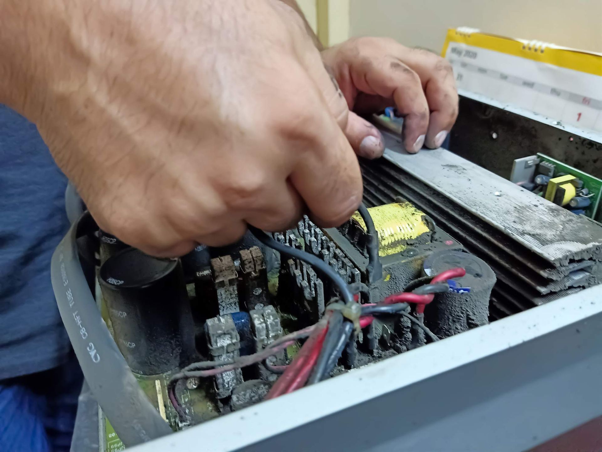 Hands working on the internal components of a welding machine