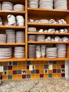 A kitchen with a lot of plates and cups on the shelves