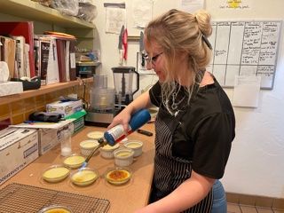 A woman is pouring liquid into a bowl of food.